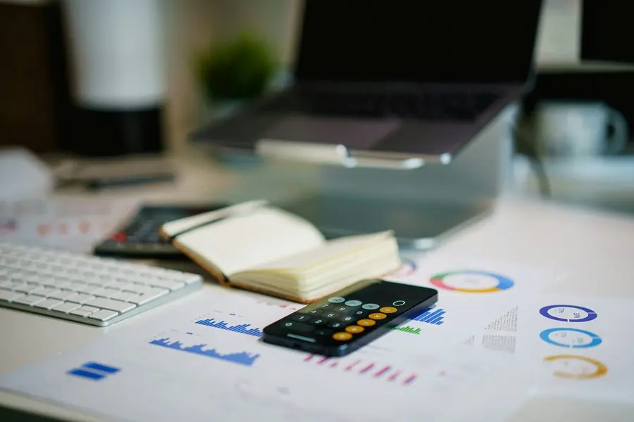 Financial planning desk with a laptop, charts, and calculator